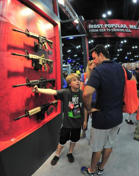 Hét végi program az USA-ban: apa és fia Bushmaster félautomata puskákat néz az NRA (Nemzeti Fegyver Szövetség)
találkozóján
Houstonban