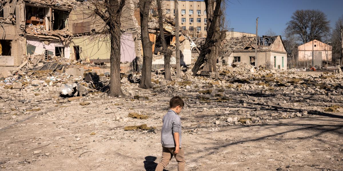 Egy gyerek sétál a lebombázott iskola előtt...