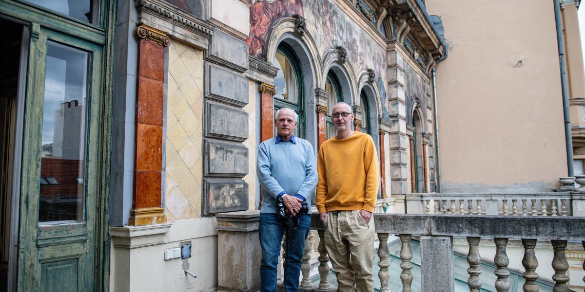 Bánkuti András fotóriporter és Baki László könyvtáros a Mai Manó Ház erkélyén, a freskók előtt