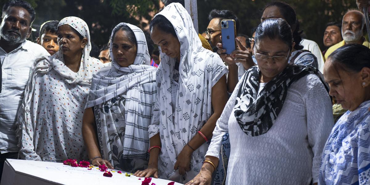 Gyászoló családtagok az egyik áldozat, Rozar David Christian koporsójánál vasárnap Ahmedabadban