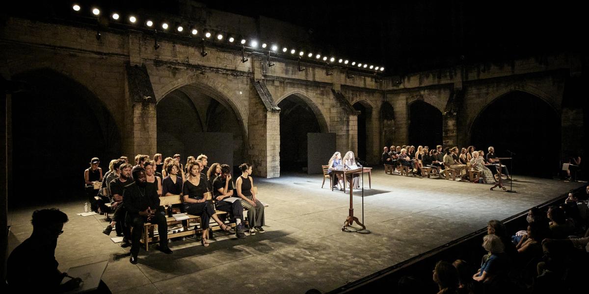 A színpadi látvány egy bírósági tárgyalóterem elrendezését idézte a Karmeliták kolostorának boltívei előtt