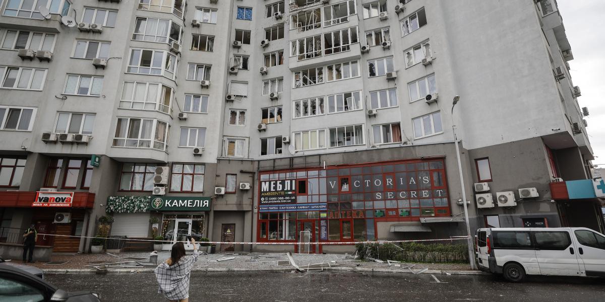 A rongálás nyomait fotózza egy nő egy kijevi lakótömbnél, amelyet orosz légicsapás ért 2025. július 28-ra virradóan