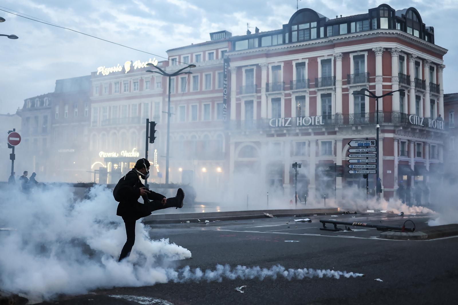 Könnygázgránátot rúg vissza a rendőrség felé egy francia tüntető egy héttel a nyugdíjreform szavazás nélküli elfogadtatása után.