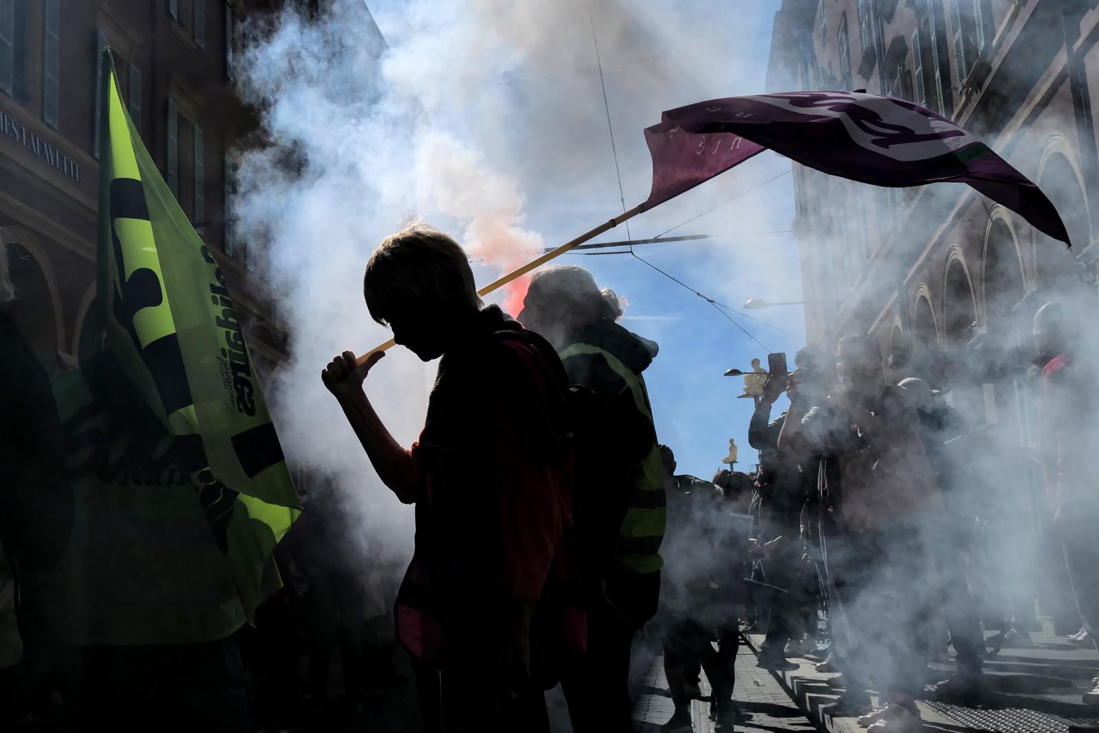 Könnygázgránátot rúg vissza a rendőrség felé egy francia tüntető egy héttel a nyugdíjreform szavazás nélküli elfogadtatása után.