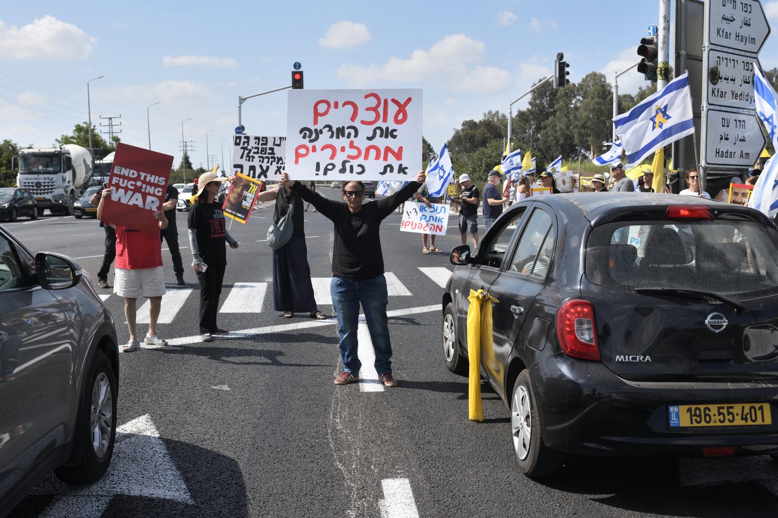 „Elhagyjuk a frontot, mindenkit kicserélünk!” - olvasható a fekete pólós férfi által készített transzparensen, utalva az izraeli vezetés leváltására.