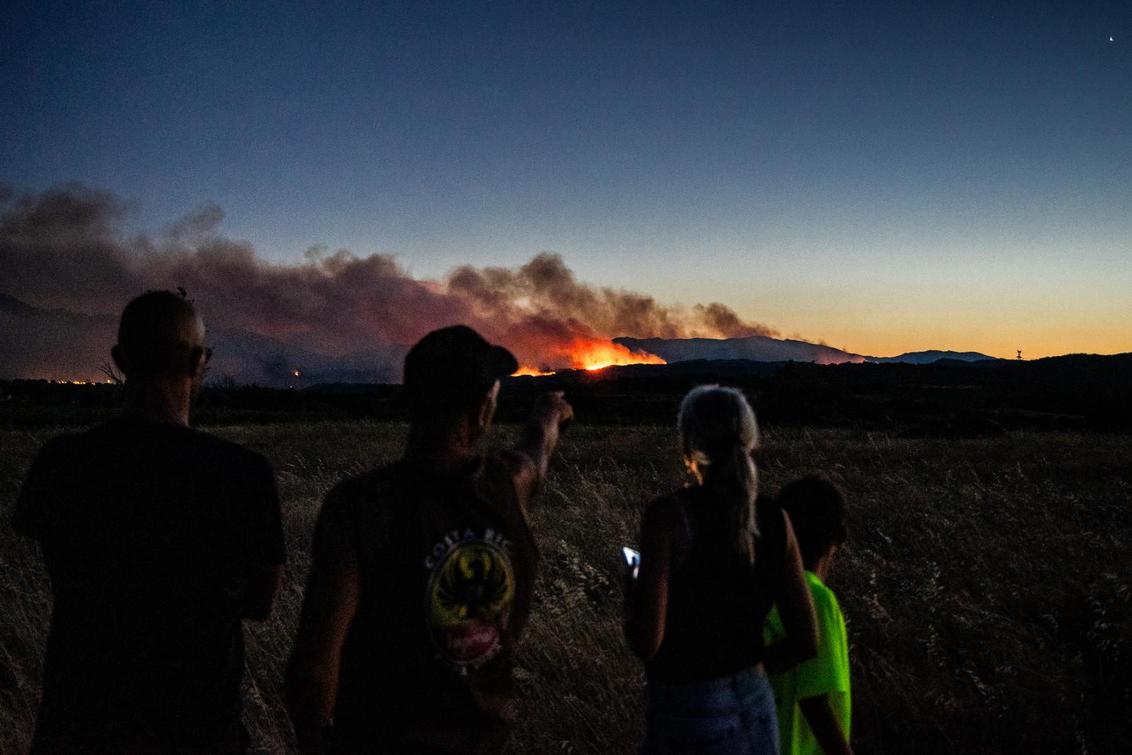 Helyi lakosok figyelik a Pireneusok-Orientales megyében, Dél-Franciaországban található Millas külvárosából az Aspres régióban egy hegygerincen túl tomboló erdőtüzet 2026. július 5-én