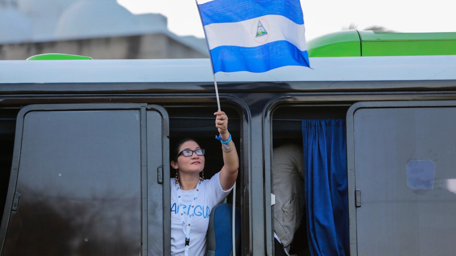 Hazája zászlaját tartja a kezében egy fiatal nicaraguai nő a találkozóra utazva