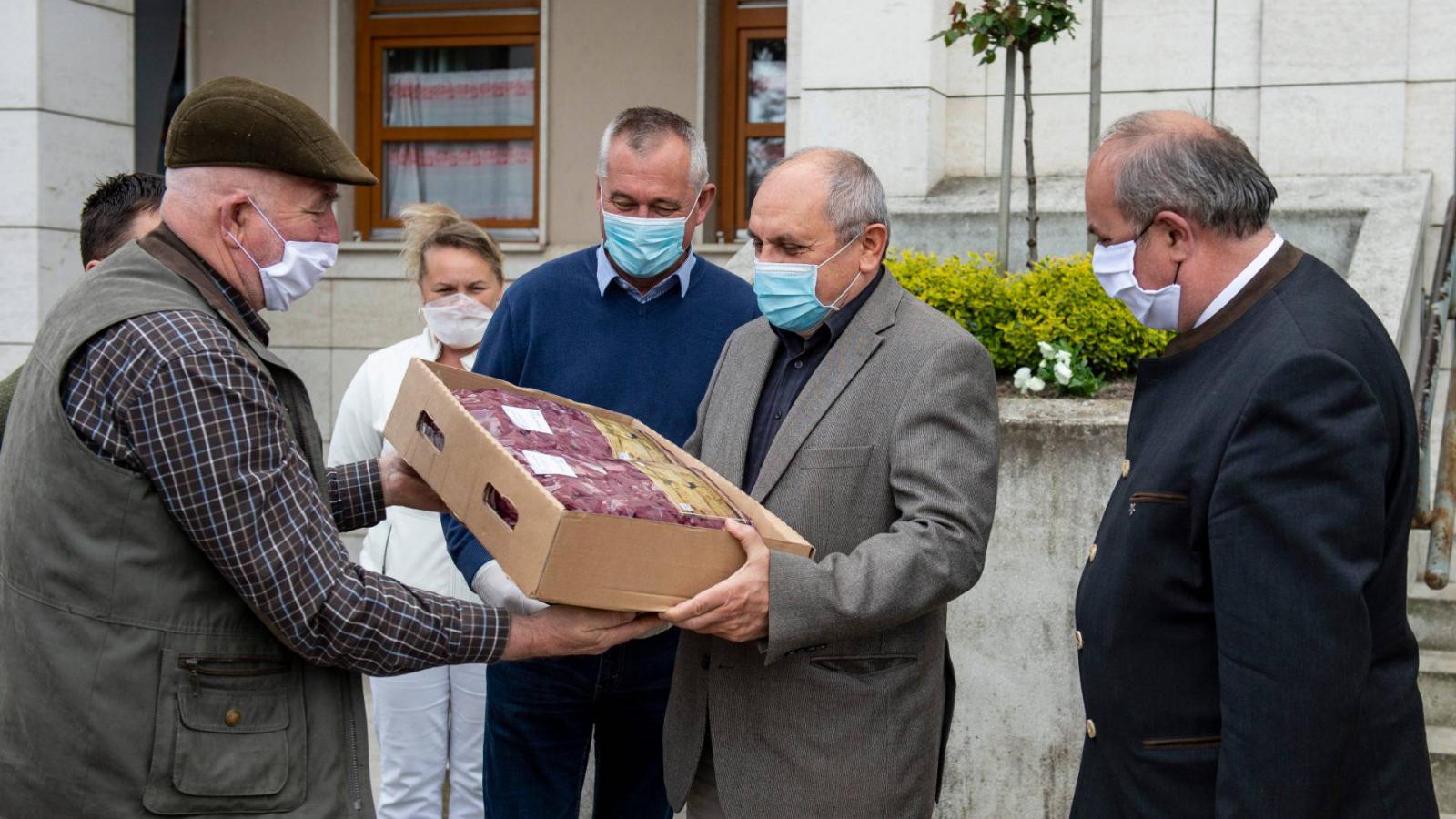 Zambó Péter, az Agrárminisztérium erdőkért és földügyekért felelős államtitkára (j) a helyi vadgazdálkodók által az egészségügyi dolgozók részére felajánlott vadhús átadásán a balassagyarmati Dr. Kenessey Albert Kórház-Rendelőintézet előtt