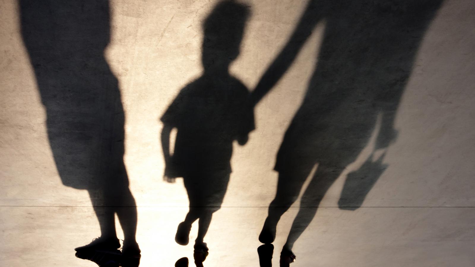 Blurry,Shadows,Of,Mother,Walking,With,Son,Hand,In,Hand