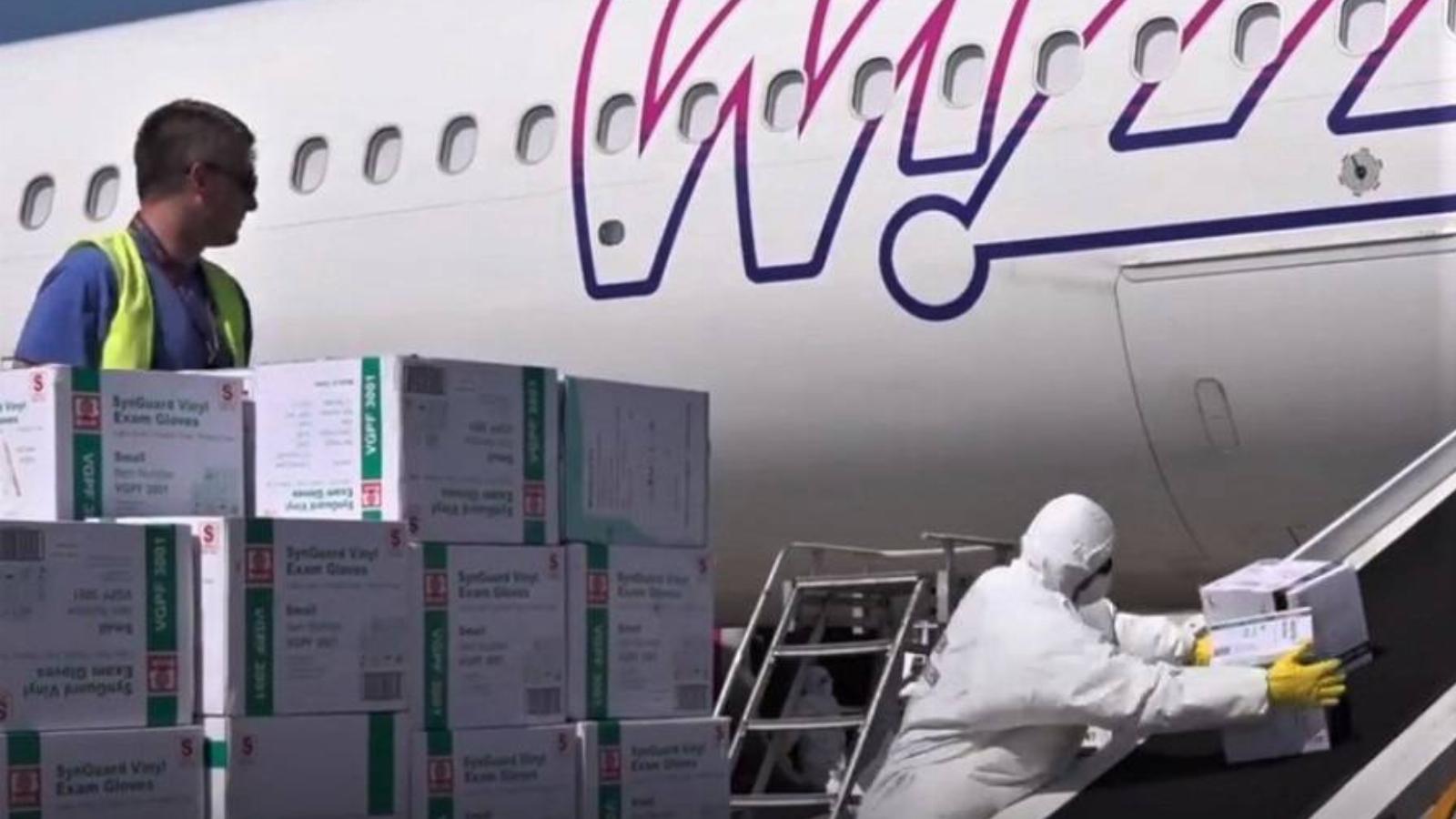 Védőruhás munkás pakolka le egy Wizz Air-gép fedélzetén hozott felszereléseket, 2020. április 18-án a ferihegyi reptéren