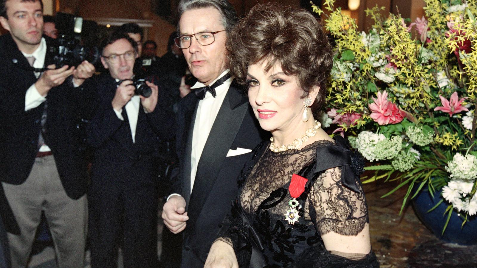 A Becsületrenddel kitüntetett Gina Lollobrigida Alain Delon francia színésszel (középen) érkezik egy párizsi fogadásra 1993. február 17-én.