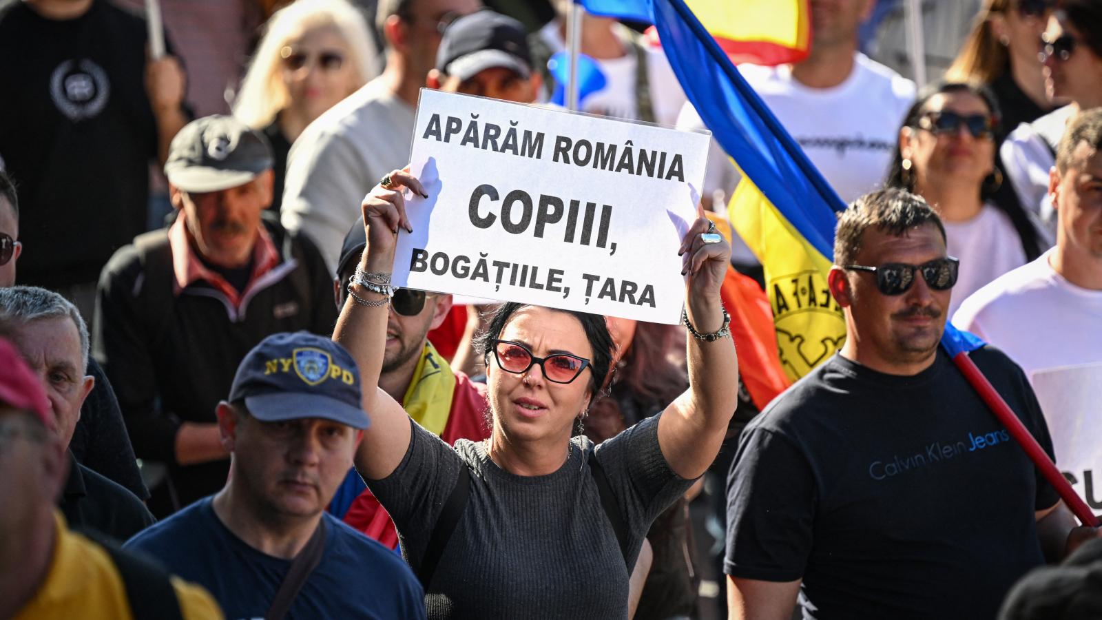 Egy nő tartja a "Megvédjük Romániát, a gyerekeket, a természeti erőforrásokat és az országot" feliratú pancartát az A.U.R. (Szövetség a Románok Egységéért) ellenzéki parlamenti párt által szervezett "Nem adjuk el az országunkat" című tüntetésen Bukarestbe