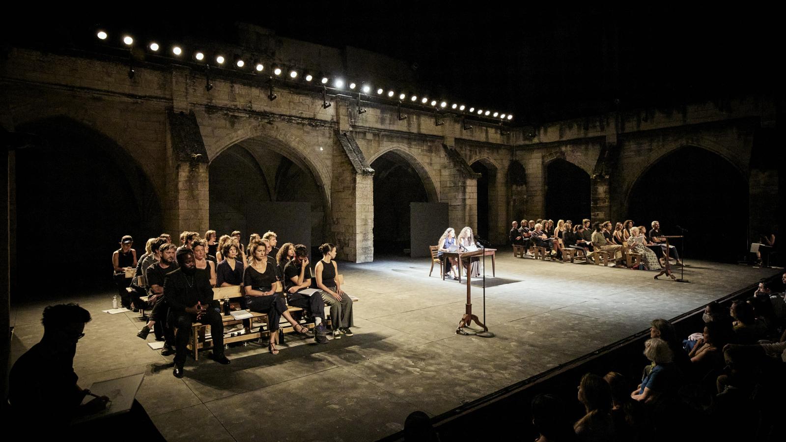 A színpadi látvány egy bírósági tárgyalóterem elrendezését idézte a Karmeliták kolostorának boltívei előtt