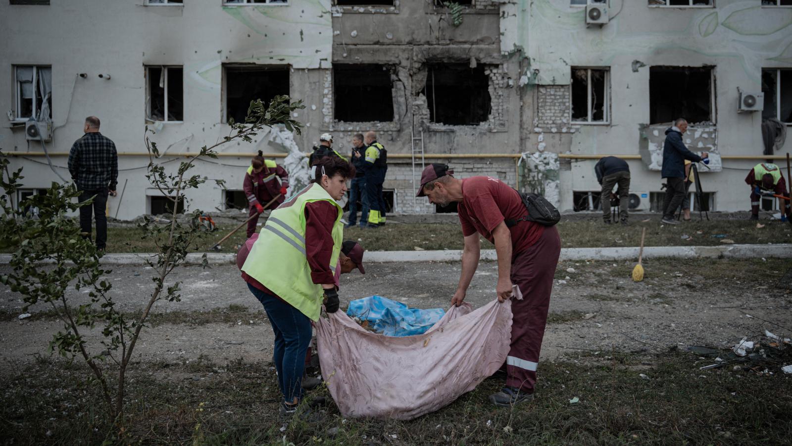 Városi dolgozók takarítják el a törmeléket egy lerombolt lakóépület elől, miután Harkivban légitámadást hajtottak végre 2025. augusztus 18-án