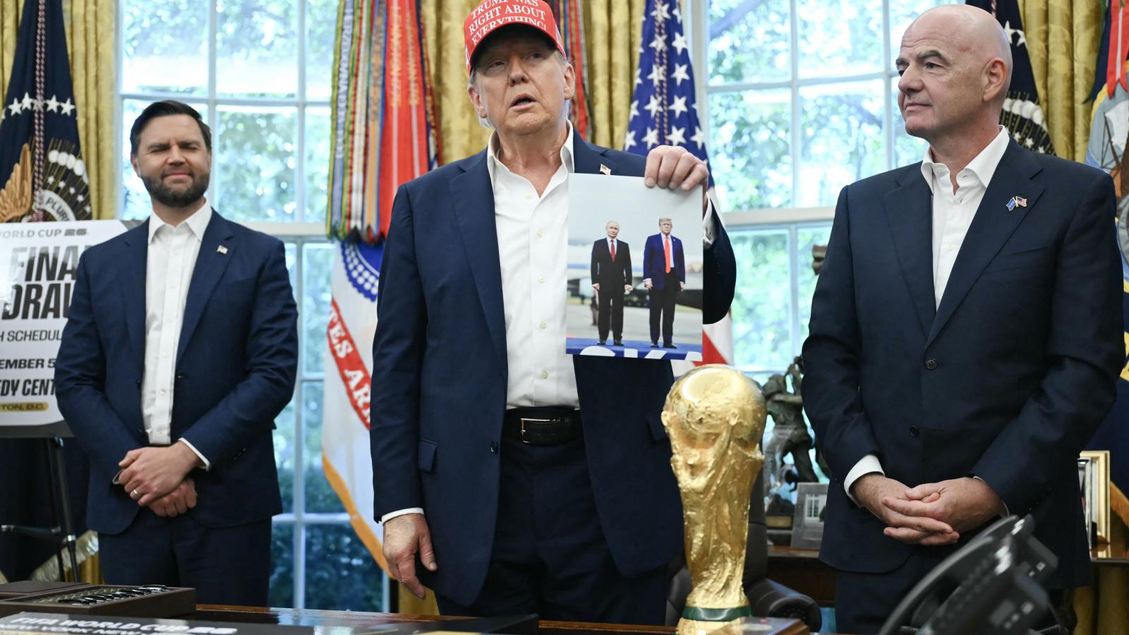 Donald Trump amerikai elnök a Fehér Házban, Gianni Infantino FIFA-elnök jelenlétében felmutat egy fotót, amely róla és az orosz elnökről készült Alaszkában