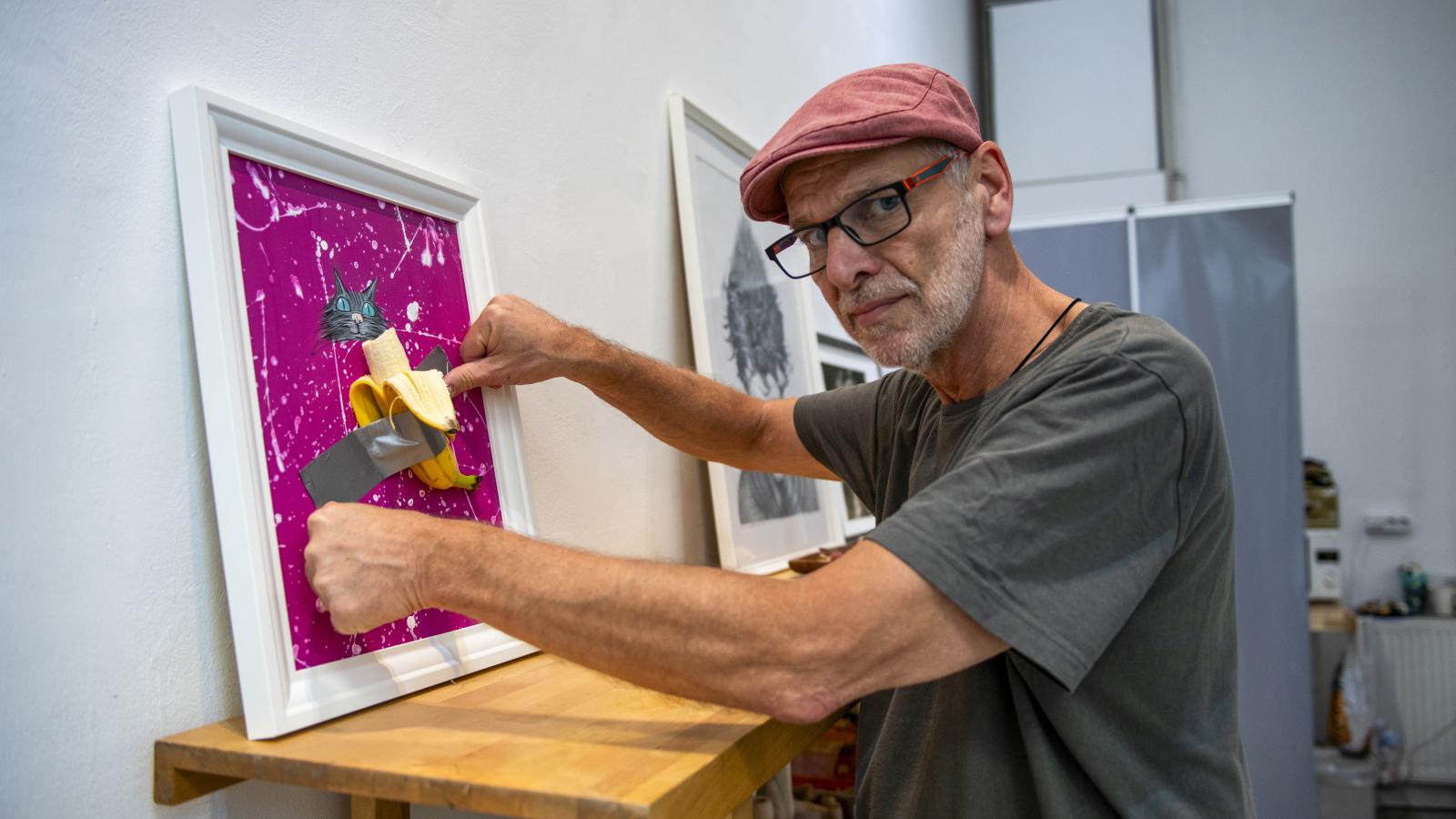 Pápai Gábor karikaturista a szombati kiállításmegnyitó előtt banánt fog ragasztani a művére