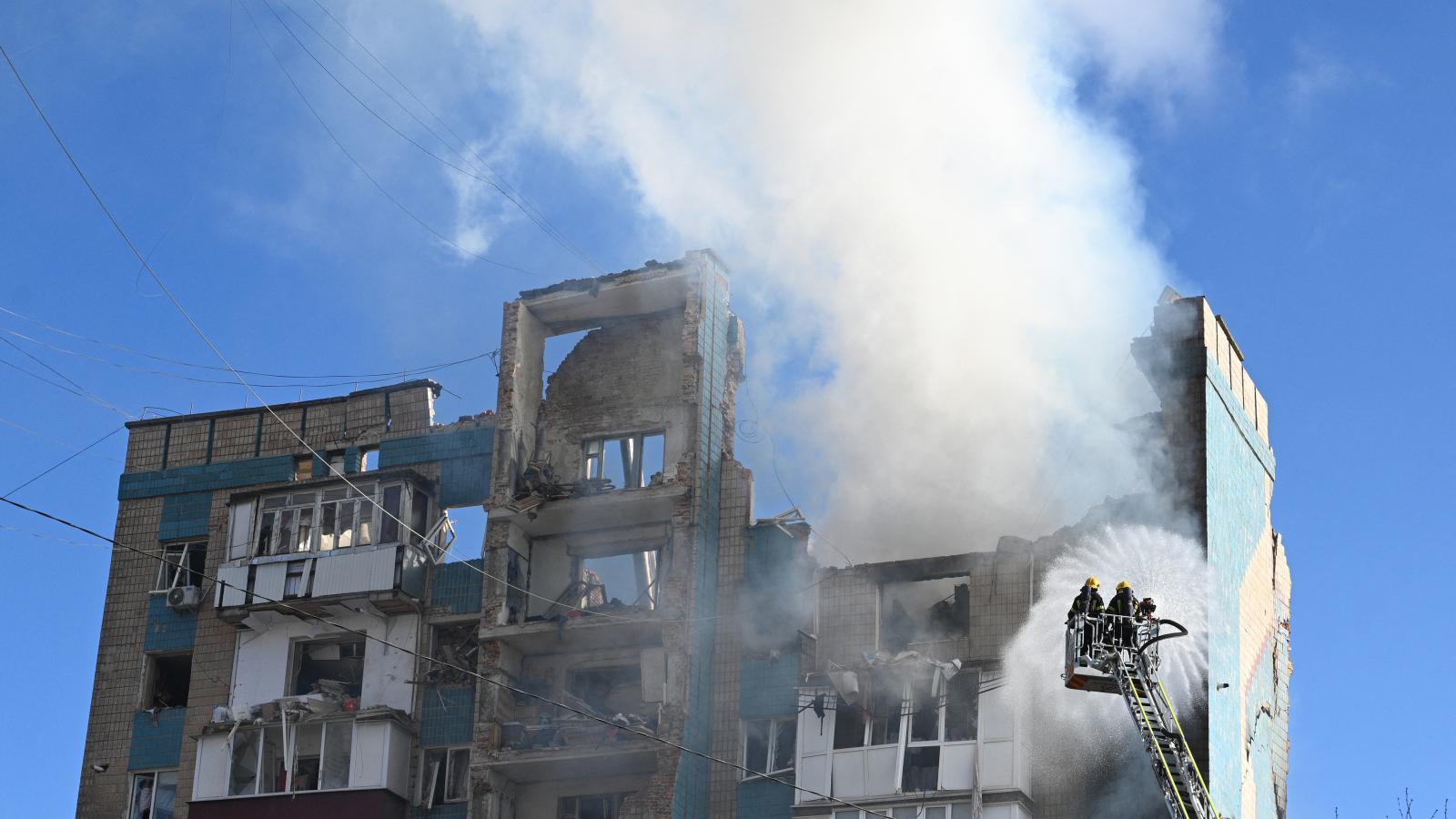 Ukrán mentőalakulatok küzdenek egy súlyosan megrongálódott lakóépület lángjaival az orosz légicsapás után.