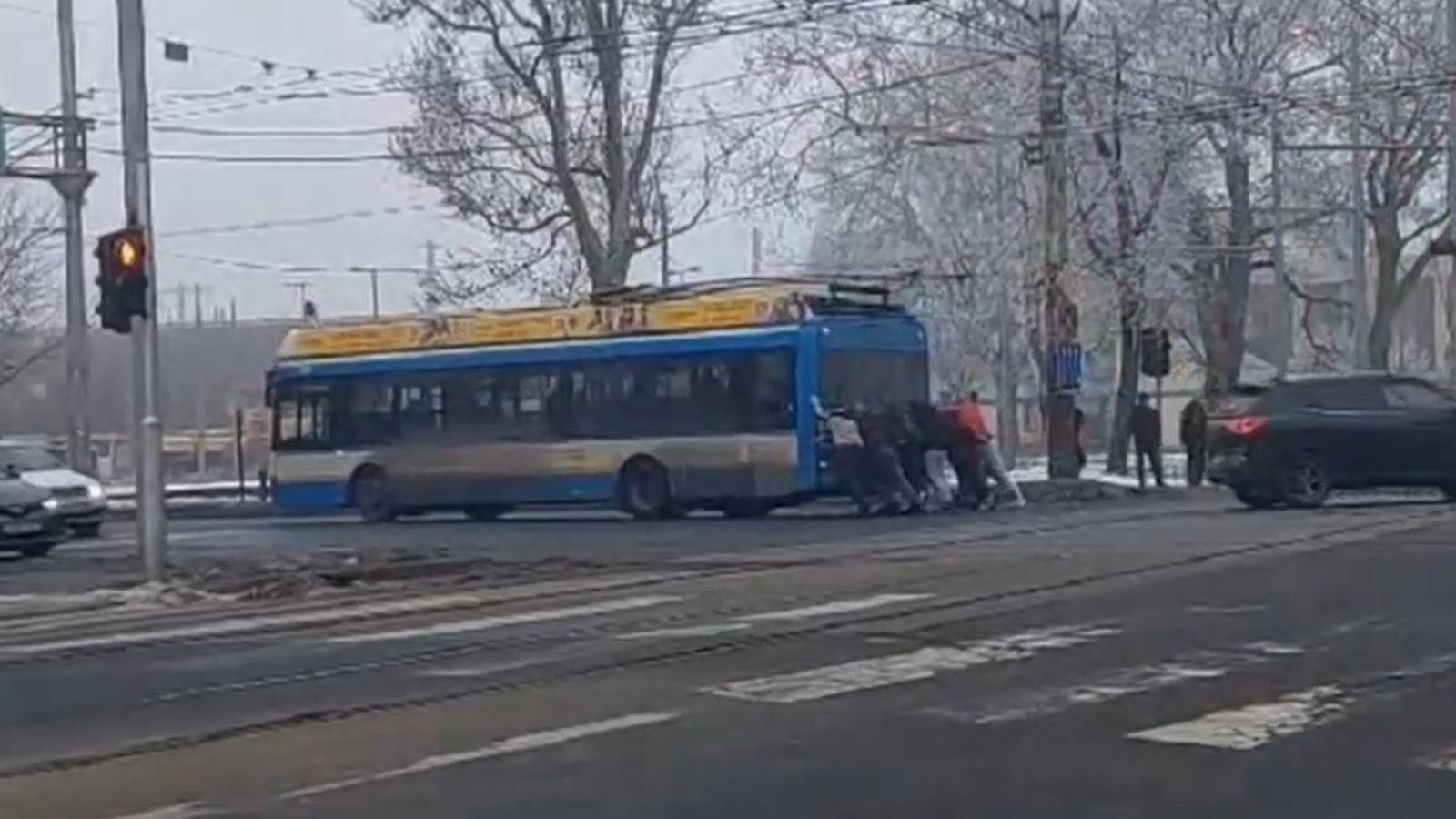 Videón, ahogy a leállt trolibuszt az utasok tolják ki a kereszteződésből Debrecenben