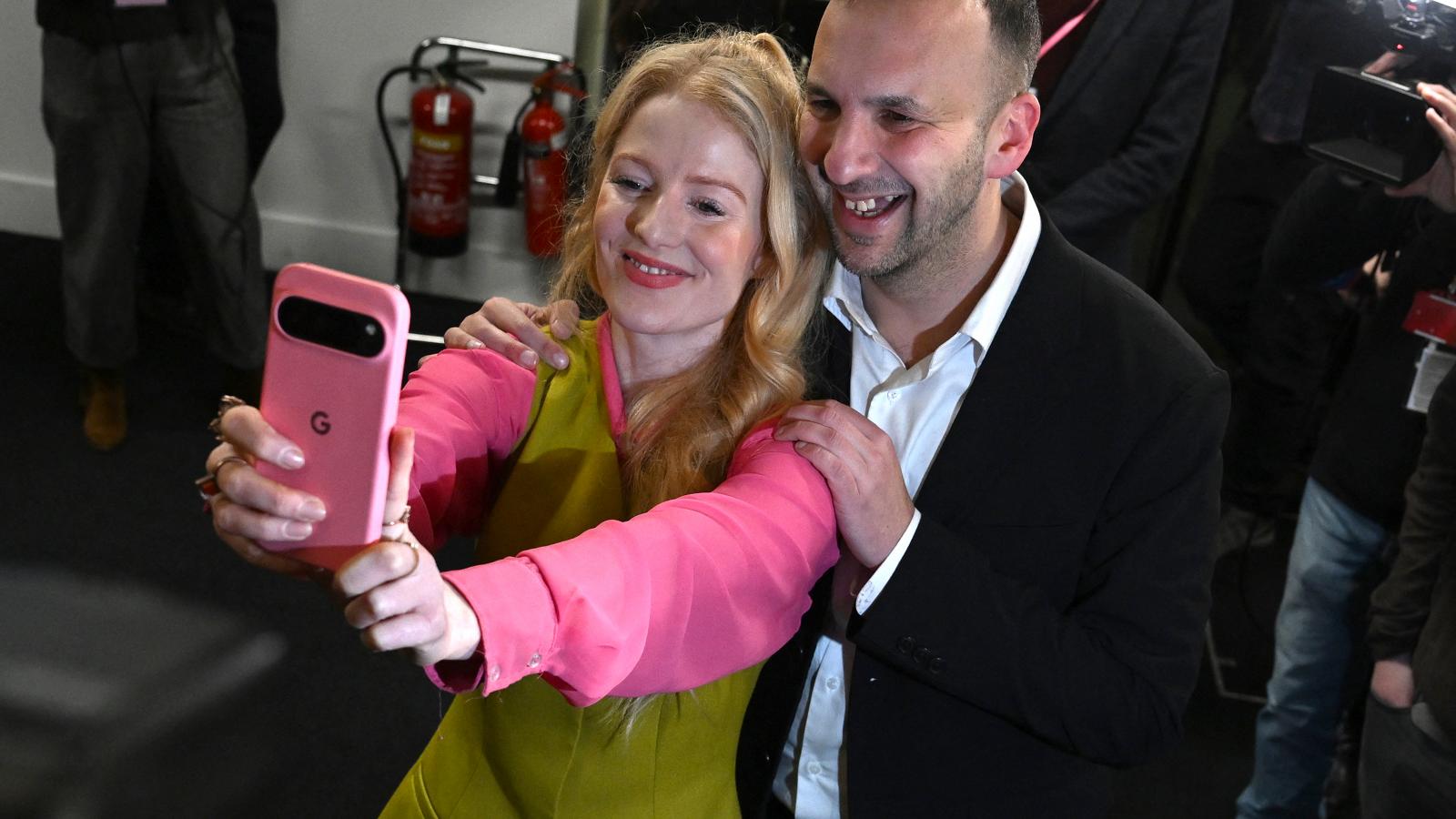 Hannah Spencer, a Zöld Párt jelöltje szelfit készít Zack Polanskival, a Zöld Párt vezetőjével, miután megnyerte a Gorton és Denton parlamenti időközi választást a Manchester Central Kongresszusi Komplexumban, Manchesterben, Észak-Angliában, 2026. február 