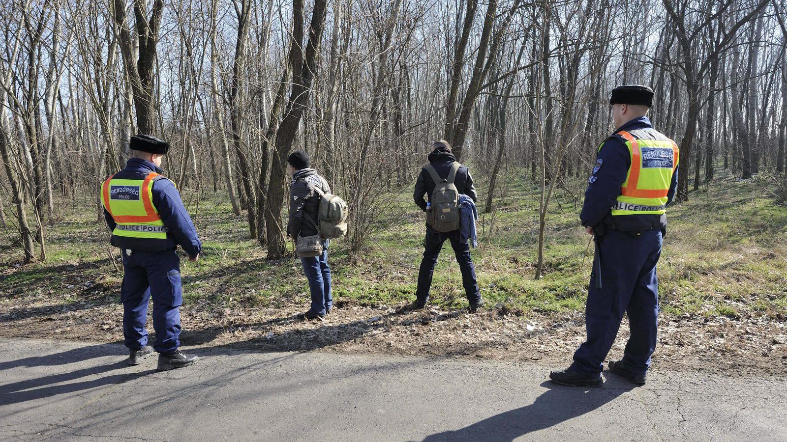 Rendőrök feltartóztatott határsértőket őriznek Ásotthalom külterületén egy korábbi felvételen. MTI Fotó: Kelemen Zoltán Gergely