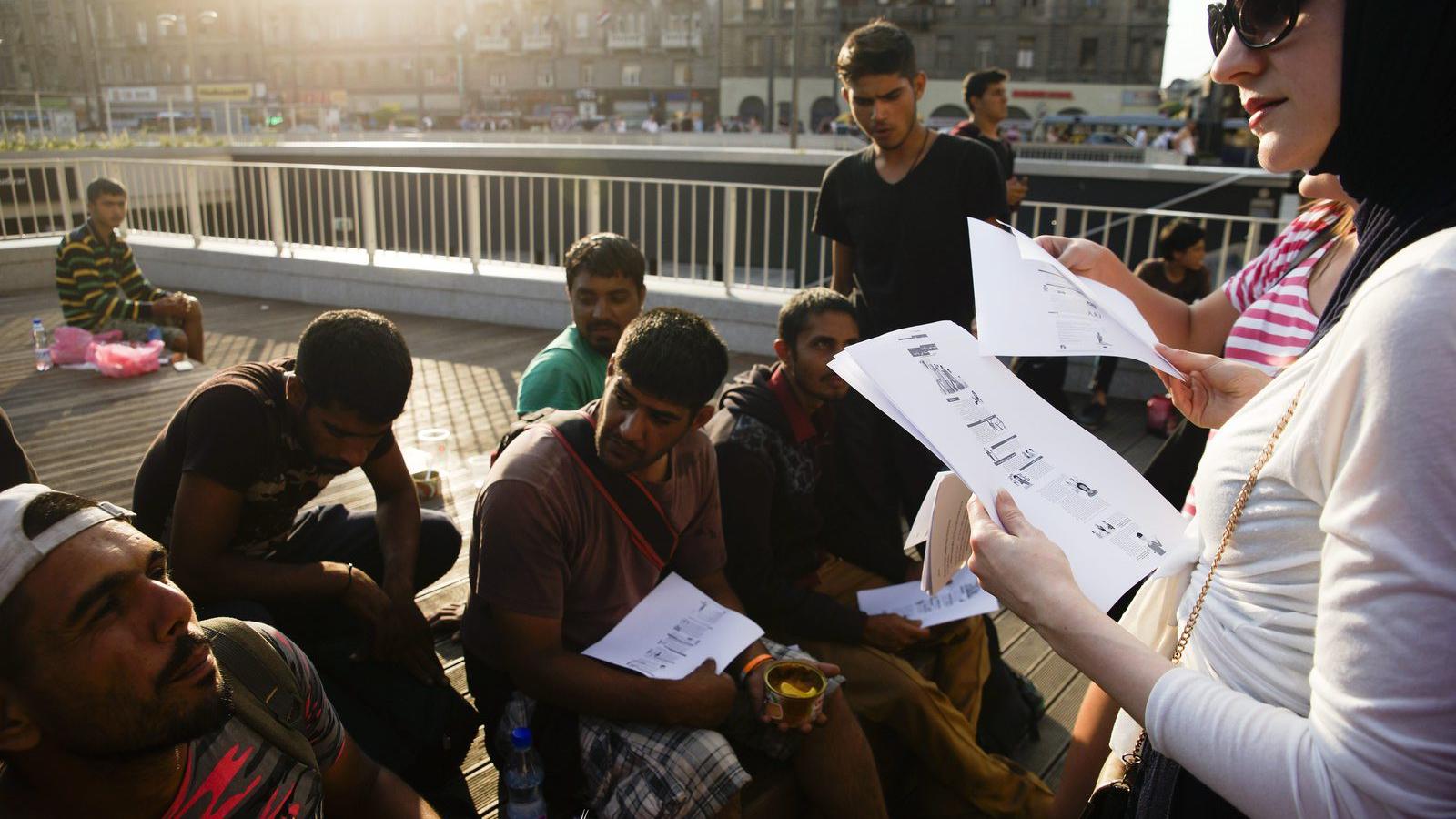  A Facebookon szerveződött civil csoport egyik tagja információkat ad migránsoknak a budapesti Keleti pályaudvar előtt 2015. júl