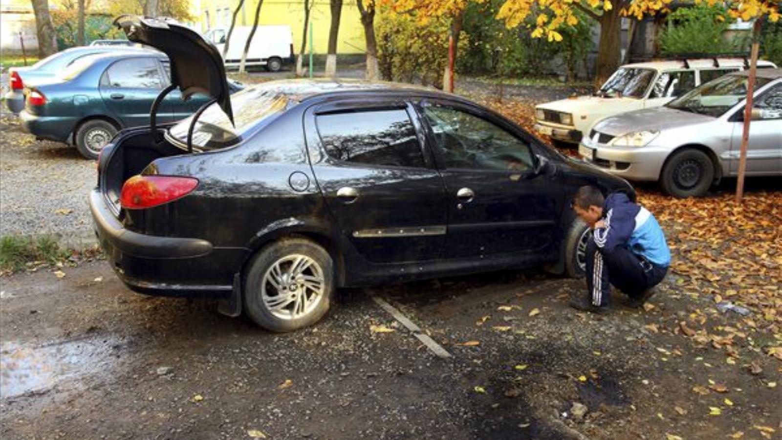 A helyi Lavriscseva utcai többszintes lakóépület előtti parkolóban felrobbantott gyalogsági gránát szilánkjainak nyomait nézi au