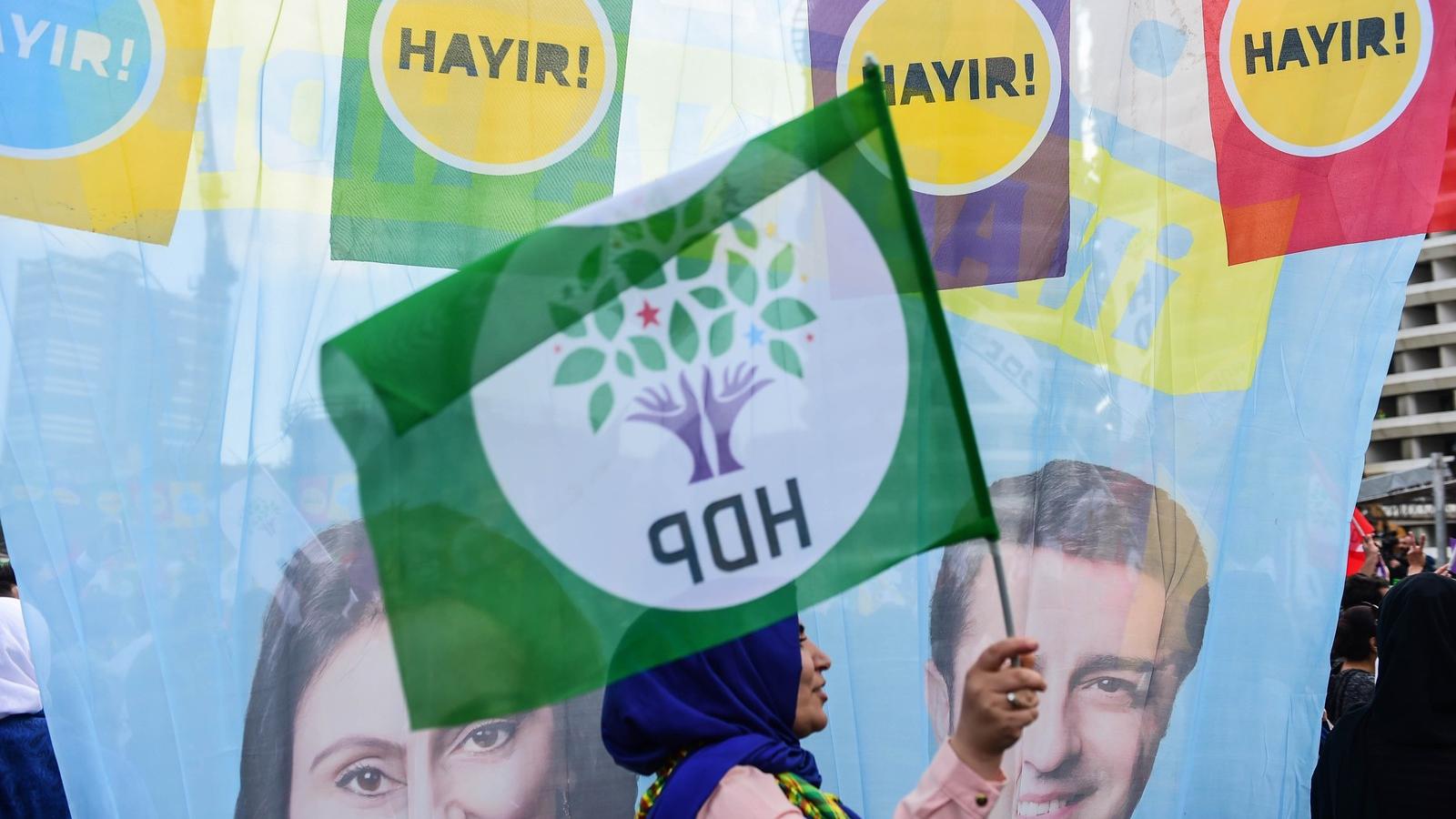 A HDP egy támogatója, háttérben pedig a párt két bebörtönzött politikusának képe. Fotó: YASIN AKGUL / AFP