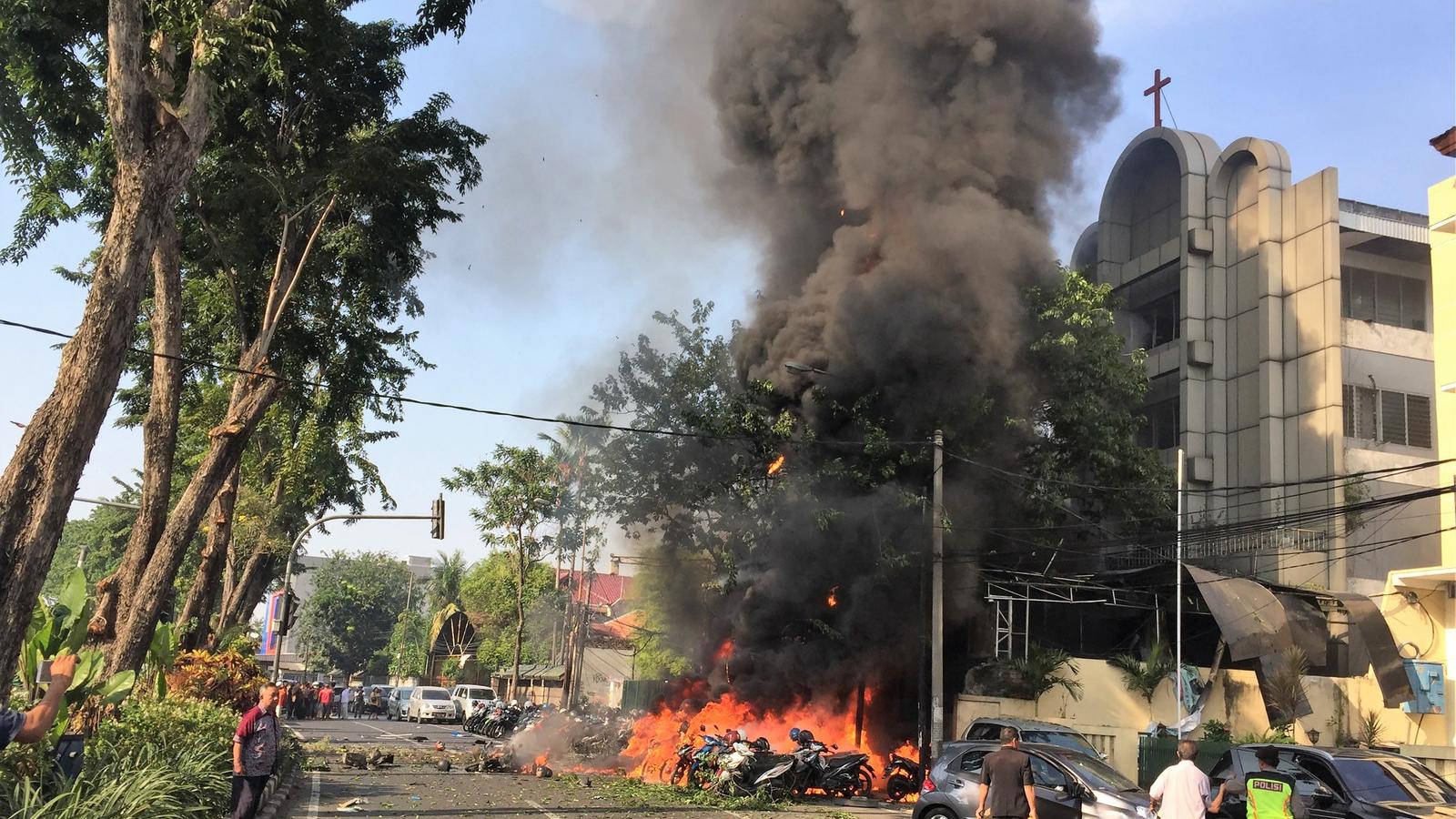 A vasárnapi merénylet után lángoló motorok egy surabayaiu templom bejáratánál. A terrortámadást hétfőn újabb követte.  Forrás: A