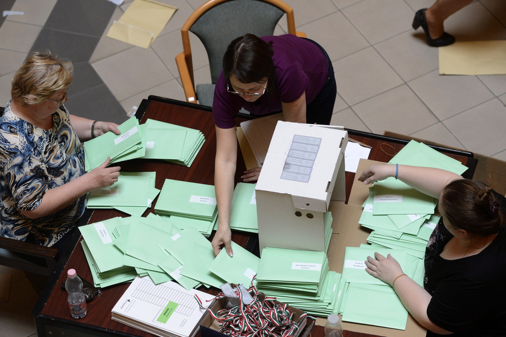 Öt asztalnál mintegy negyven irodai munkatárs végzi az urnabontást, és osztja szét a külképviseleteken szavazók voksait tartalmazó zöld borítékokat megyénként külön kartondobozokba. Fotó: Kovács Tamás/MTI
