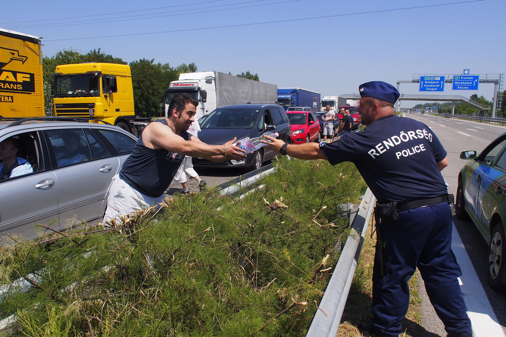 A rendőrség vizet oszt a hőség miatt a röszkei határátkelőnél. MTI Fotó: Donka Ferenc