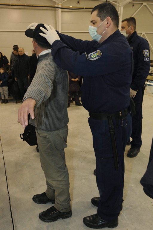 Egy rendőr átvizsgálja egy feltartóztatott koszovói férfi ruházatát