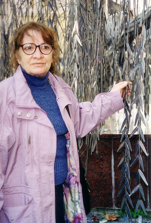 A képen Yoav Blum édesanyja a Dohány utcai zsinagóga kertjében az Emanuel-emlékfa egyik levelét fogva, melyen a holokauszt-áldozat nagymama neve olvasható.