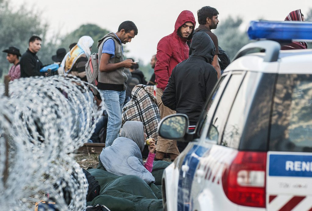 Jódolgukban csak úgy a bizonytalanságba induló "migránsok" a Röszke melletti vasúti átjárónál a magyar-szerb határon 2015. augusztus 25-én reggel. MTI Fotó: Ujvári Sándor